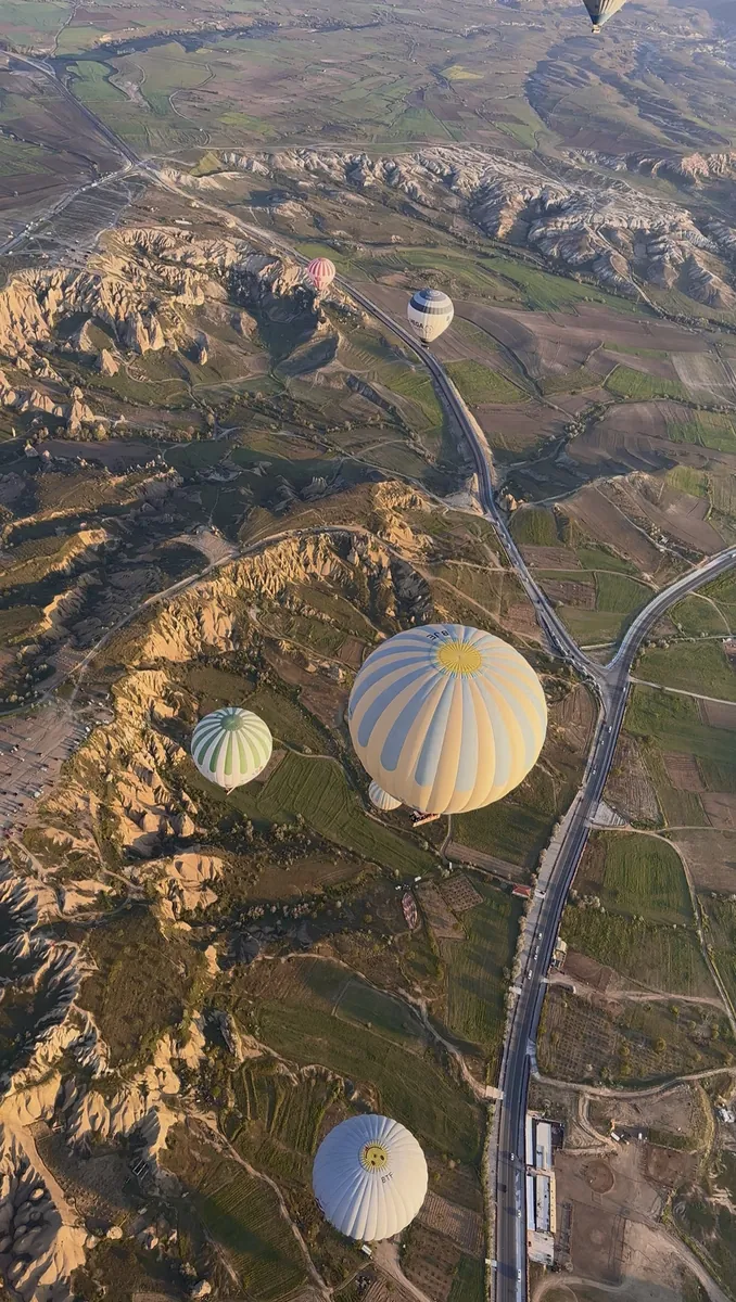 Bird's-eye aerial view of hot air balloons over Cappadocia valleys